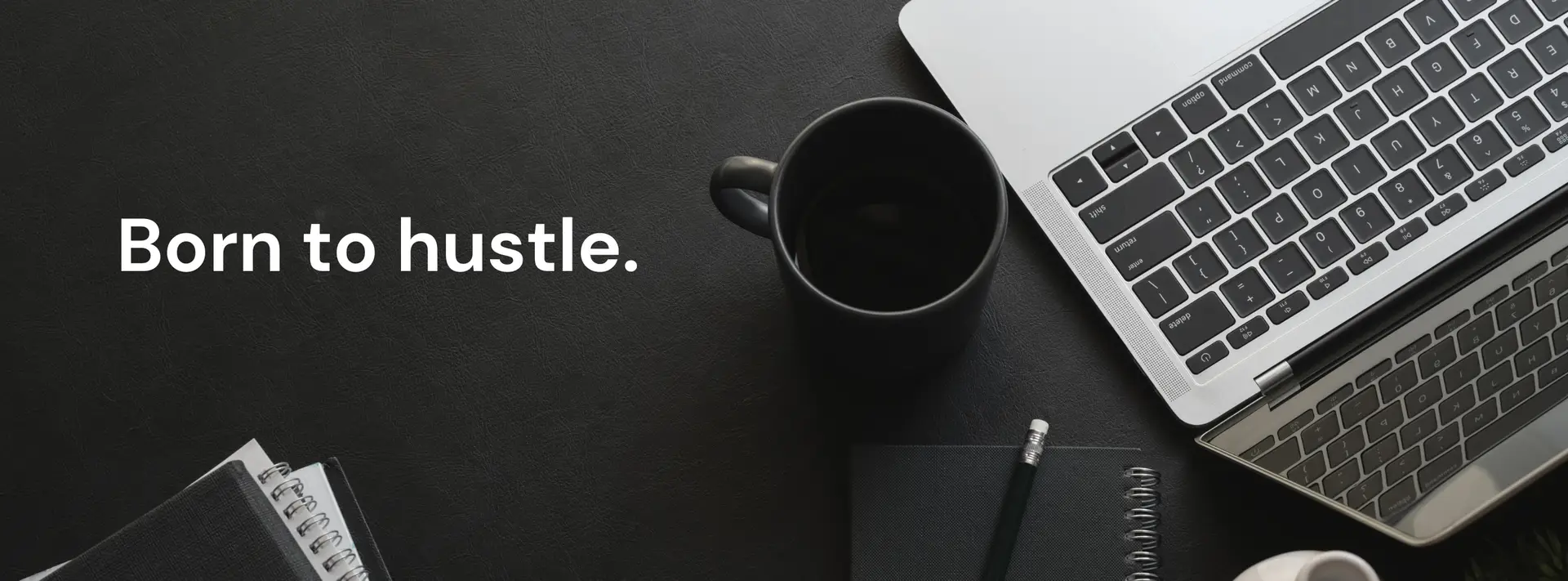 Born to hustle text on a sleek black workspace with a laptop, coffee mug, notebook, and pen.
